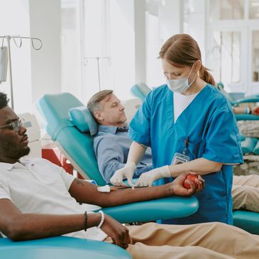 Nurse assisting a man donating blood in a clinic.