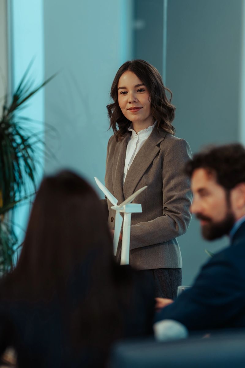 Young businesswoman presenting a wind turbine model to her colleagues during a meeting in a modern office