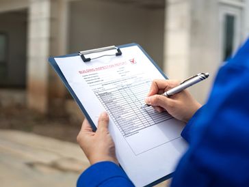 Person filling out a form on a clipboard.