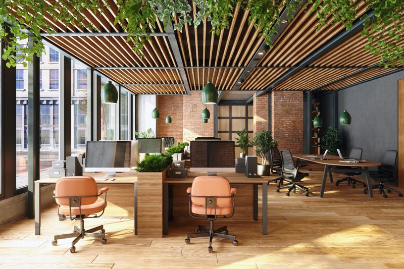 Sustainable open-plan modern office featuring desks, chairs, hanging lights, and plants