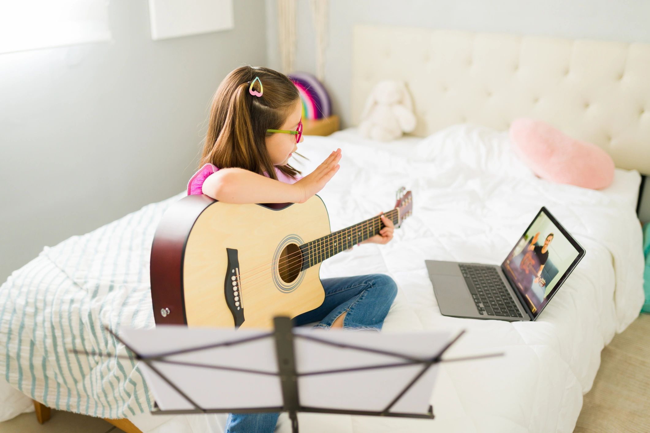 Girl learning guitar via online lesson at home.