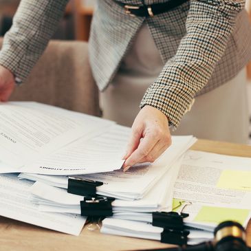 Person organizing legal documents on a desk.