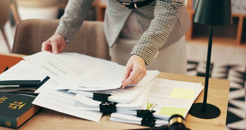 Hands, admin and stack with legal documents at office for review, inspection or investigation. Person, paperwork and secretary for deadline, time management or gavel for law, justice or case analysis