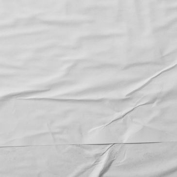 A close-up of wrinkled white fabric or paper surface.