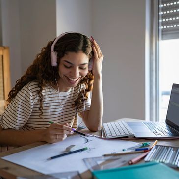 Young woman happily drawing while listening to music with headphones.