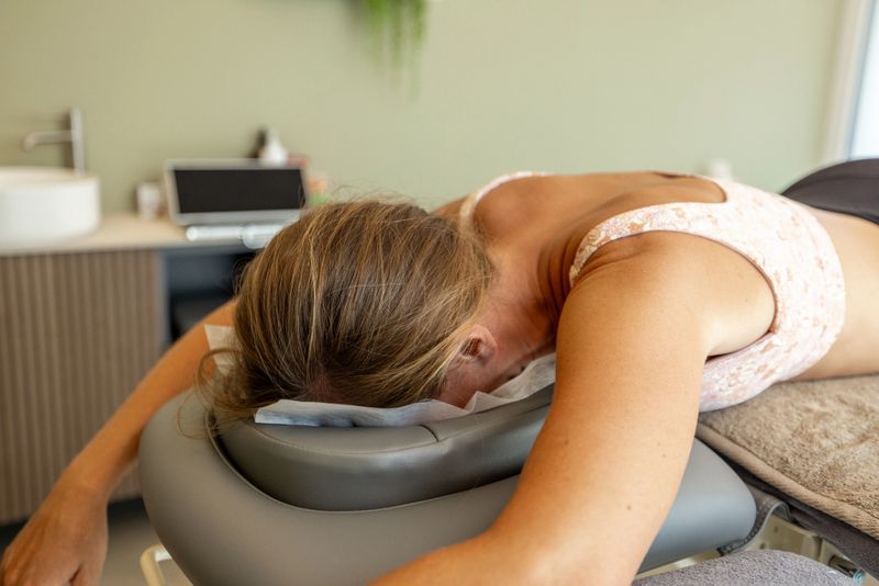 Woman lies face down on a massage table during physiotherapy. Relaxation in a calm clinic setting. Therapy session focused on healing and wellness.