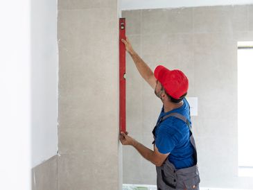 Worker measuring bathroom wall