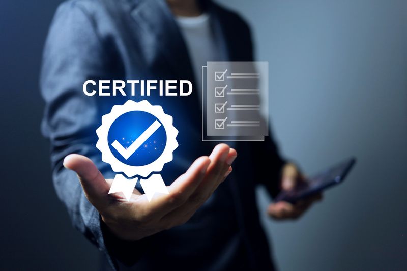 Businessman holding a certification with check mark on the certificate document system that has certified to a quality standard passed audit according to industry standards