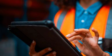 Person wearing safety vest using tablet.