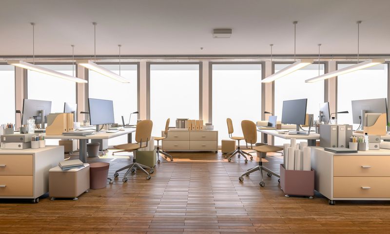 Stylish and modern office flooded with natural light, featuring desks with computers placed near large windows. Design tools, paper rolls, and documents scattered across the workspace suggest activities like graphic design, brainstorming, project planning, and creative work in a vibrant and productive environment.. Digitally generated 3d rendering.