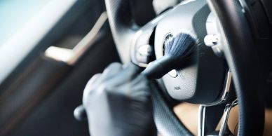 Person cleaning car steering wheel with brush.