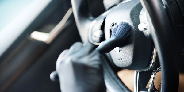 Person cleaning a car steering wheel with a brush.