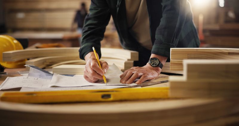 Workshop, carpenter and hands with pencil for blueprint, manufacturing and architecture project. Closeup, business person and design with drawing for carpentry, furniture renovation and creativity
