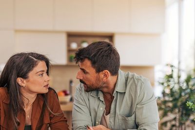 Couple discussing finances with piggy bank and notebook on table.