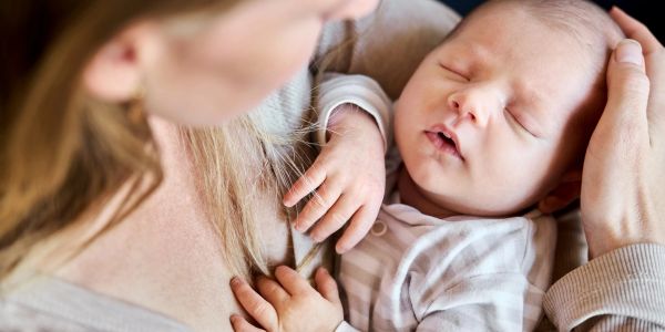 A mother tenderly cradling her sleeping baby.