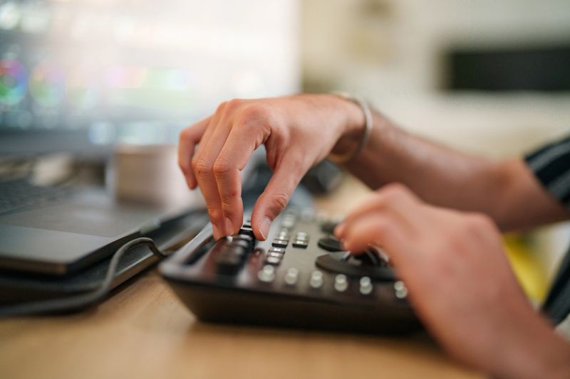 A close-up captures the hands of a video colorist using a color board at his work desk, meticulously preparing for a creative project. The scene reflects dedication to color accuracy and meticulous attention to detail in photography.