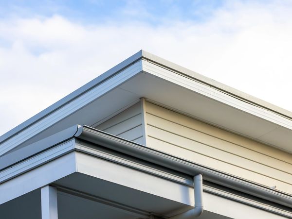 Modern house roof corner with white siding and gutter system.