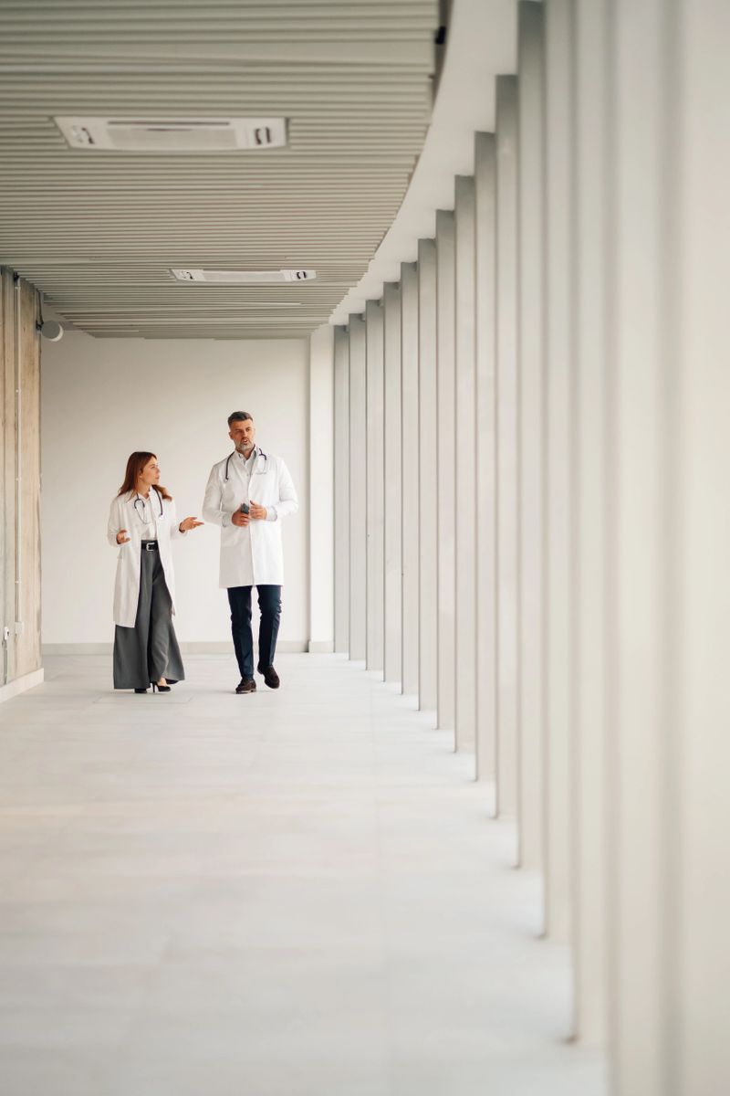 Two doctors walking through a modern hospital corridor, discussing patient care and sharing insights about medical treatment and health