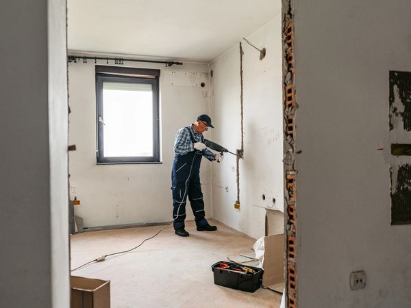 Man using drill on wall.

