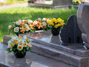 Flowers placed on a polished gravestone in a cemetery.