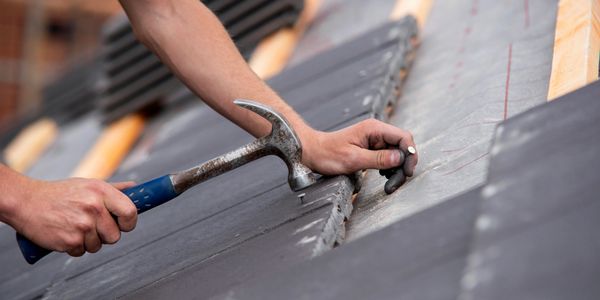 Person using a hammer to fix roof tiles.