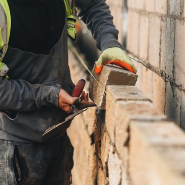 Construction worker laying bricks on a wall.