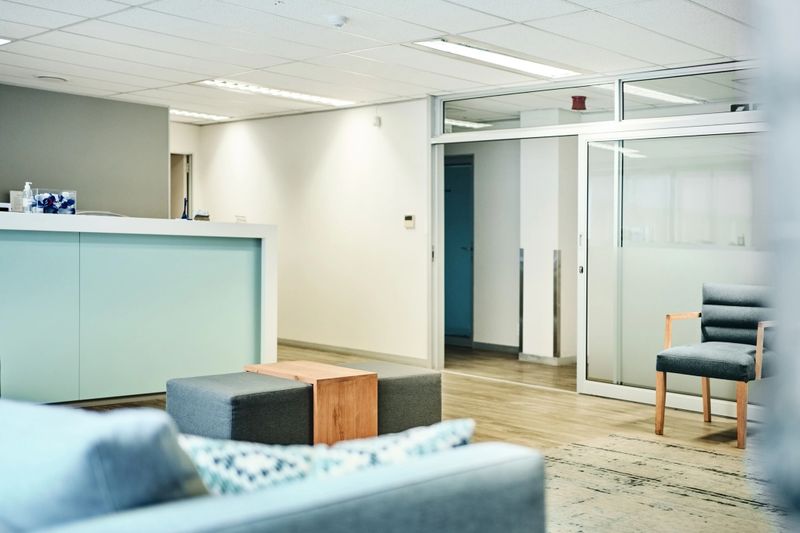 Empty medical waiting room with reception desk and chairs in clean and well-lit clinic lobby
