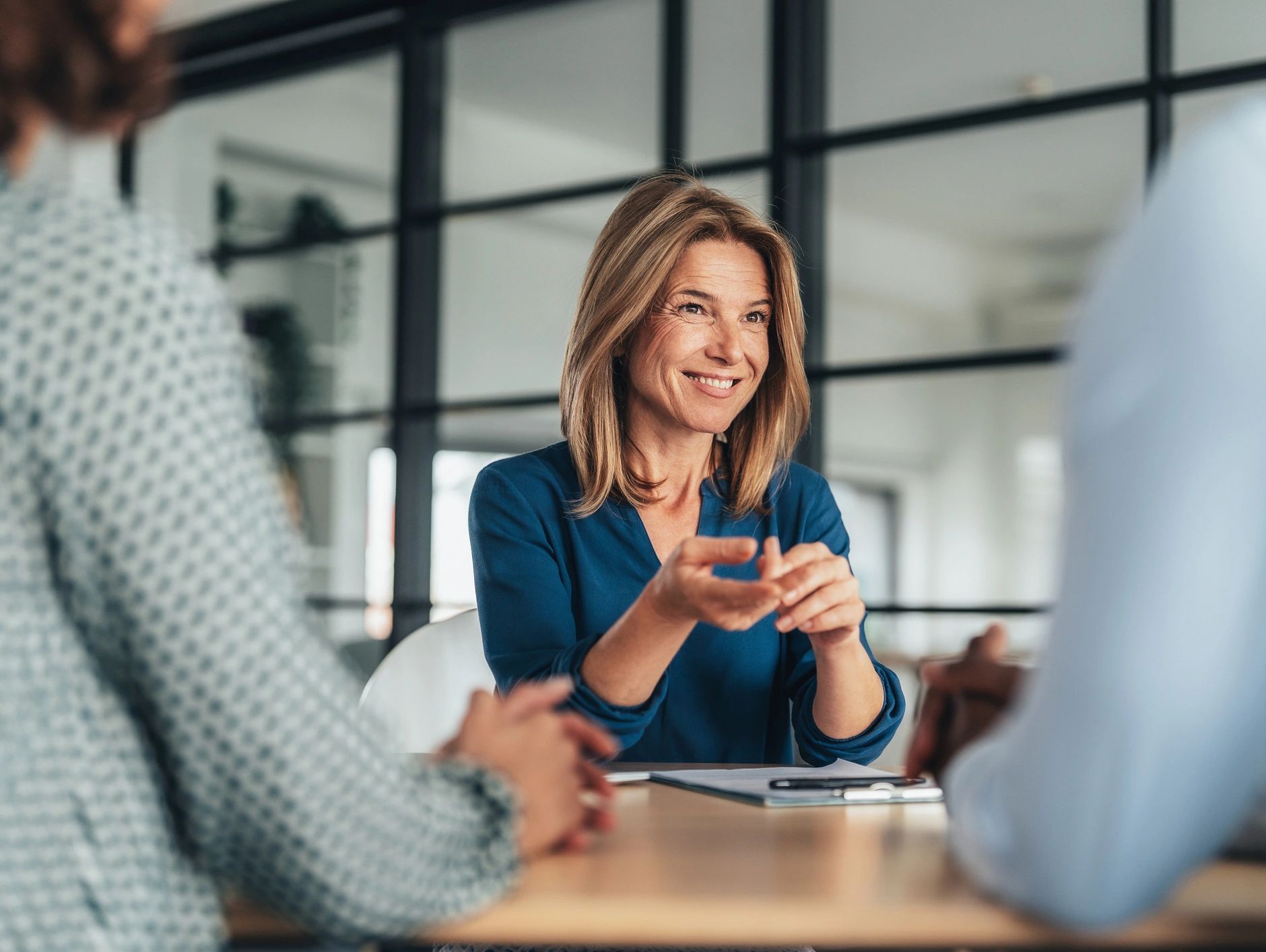 Smiling woman in a meeting, engaging with colleagues.