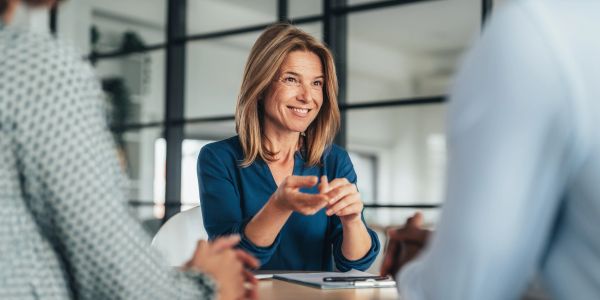 Mujer sonriente conversando en reunión de negocios.