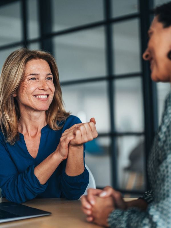 Two women engaged in a friendly conversation at a table.