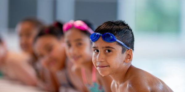A boy in blue goggles at a swimming pool.