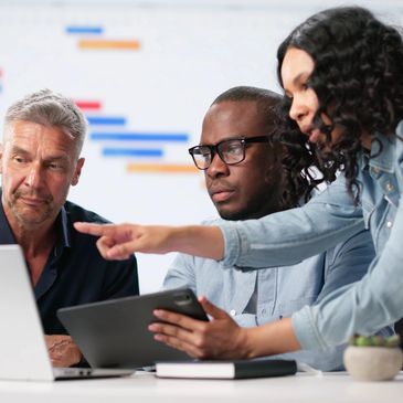 Three professionals discussing work at a laptop.