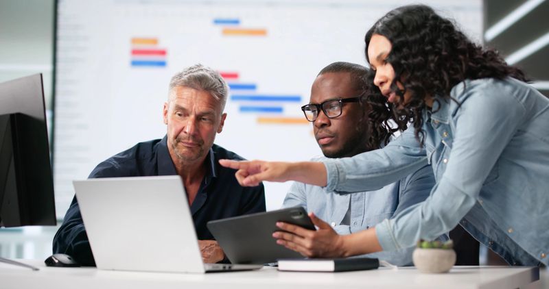 Diverse Corporate Team Using Gantt And Kanban Boards For Project Management. Man And Woman Work Together In Office