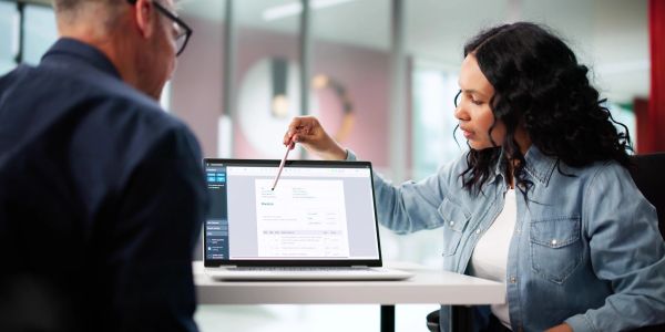 Woman explaining document on laptop to man.