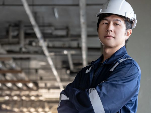 Confident engineer in a safety helmet and blue coveralls at a construction site.
