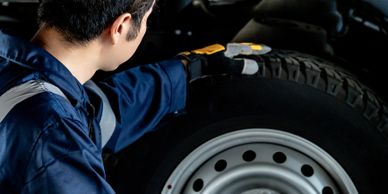 A mechanic inspects a car tire closely in a garage.