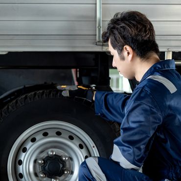 Mechanic inspecting a truck tire closely.