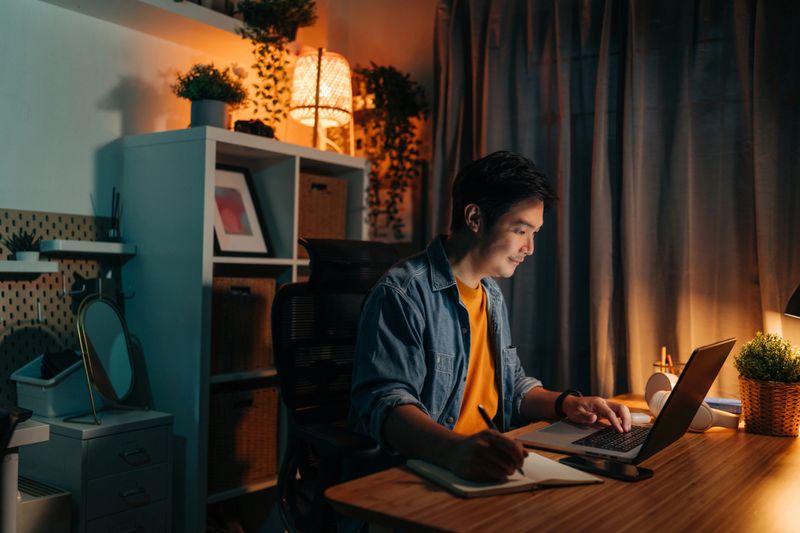 Entrepreneur working late at night with laptop and notebook in home office