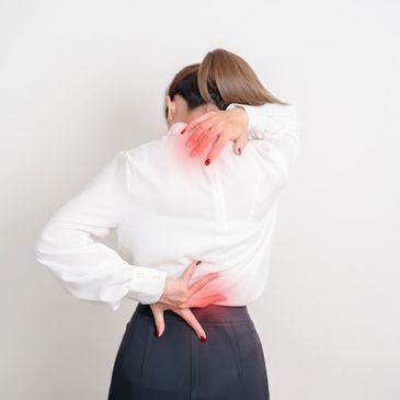 Woman in white blouse holding her back and neck in pain.