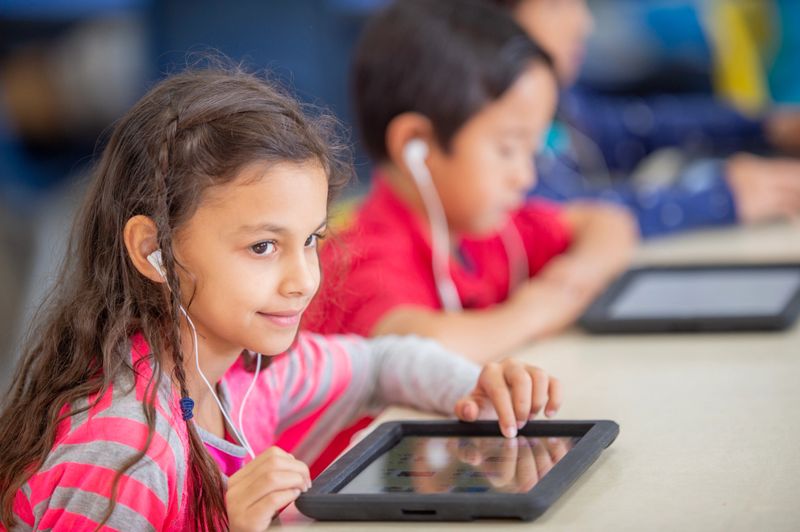 Children engaged in educational activities using tablets, fostering learning, focus, and creativity. The classroom promotes the use of modern technology as a tool for young students' academic and personal growth.