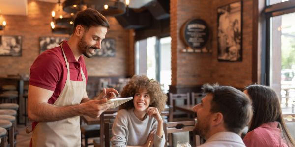 Waiter taking an order from smiling customers.