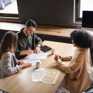 Three people collaborating on documents at a table.
