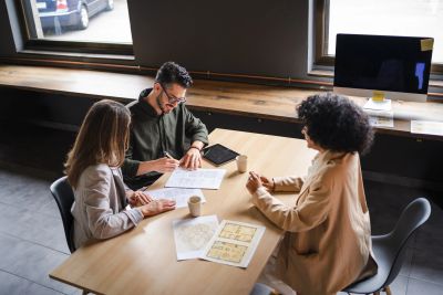 Three colleagues discussing documents around a table in an office.