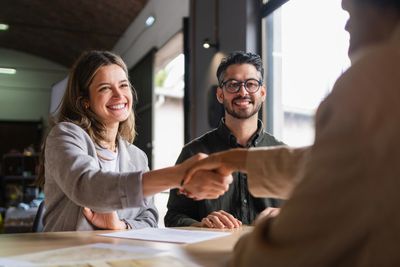 Two people smiling and shaking hands during a meeting.