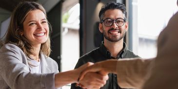 Two people smiling and shaking hands.