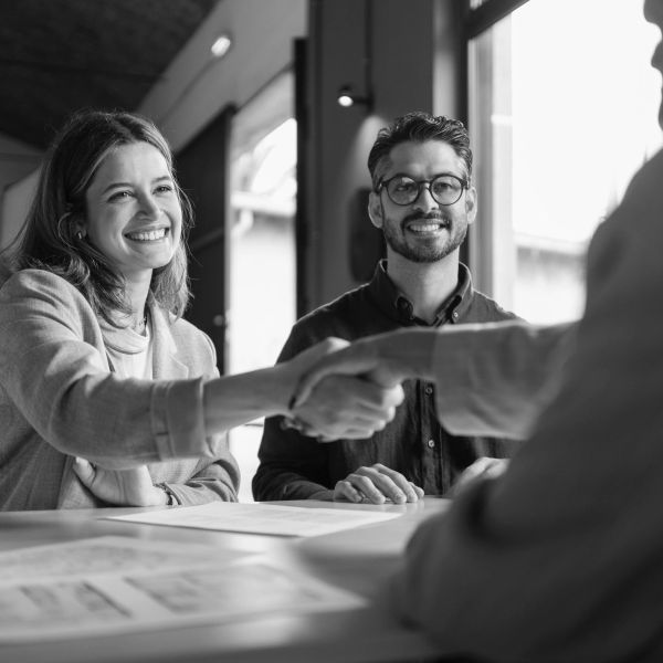 Two people smiling while shaking hands with another person.