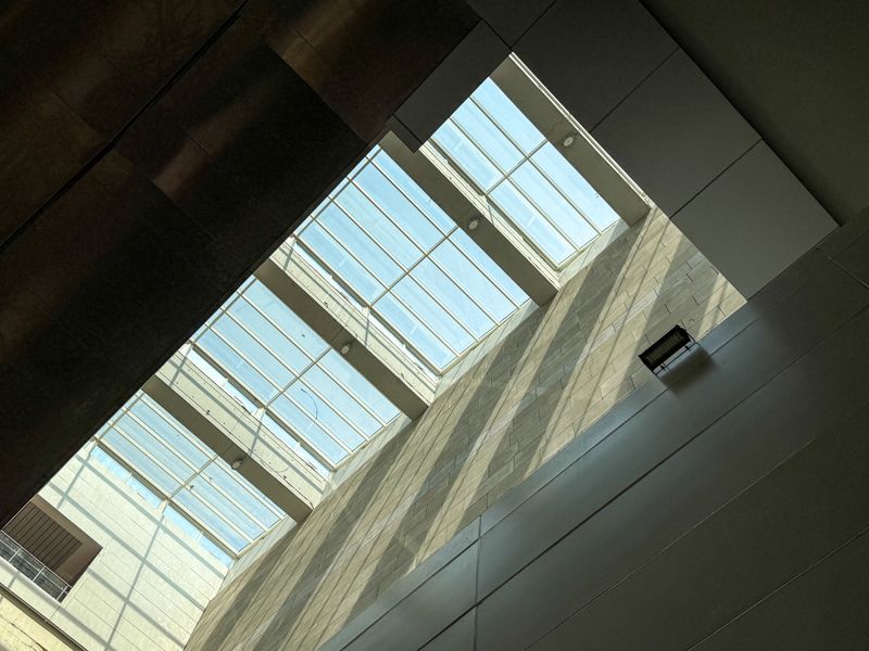 A large open space with a clear roof and a lot of sunlight. The sunlight is shining through the windows, creating a bright and airy atmosphere