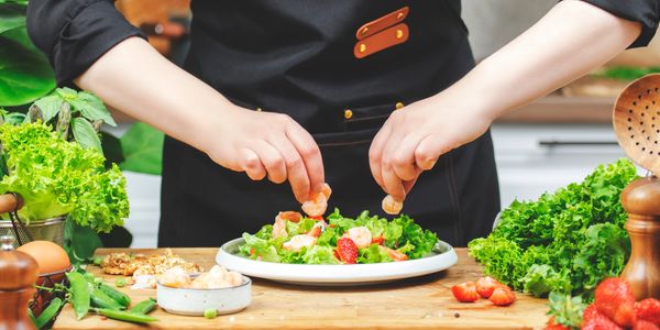 Person preparing a fresh salad with lettuce and tomatoes