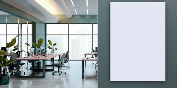 Modern office with large windows and blank vertical poster on wall.