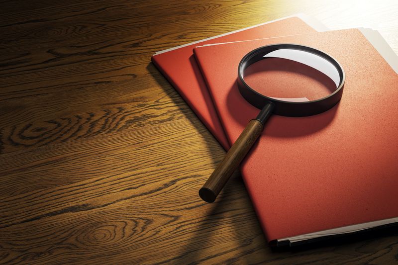 Close up Tablet Gadget and Magnifying Glass on Top of Open Notes, Resting on Wooden Table at the Right Edge, with Copy Space on Left Side for Texts.